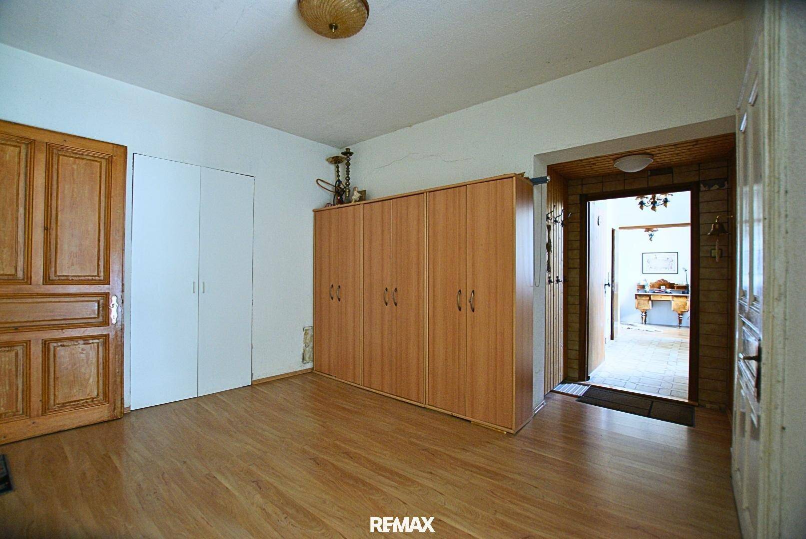 Schlafzimmer mit Laminatboden, großem Kleiderschrank und Holztüren, die den Raum abgrenzen.