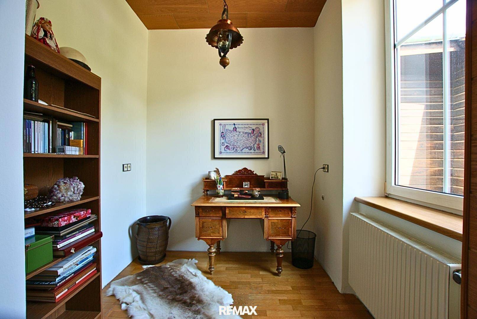 Gemütliches Arbeitszimmer mit Holzboden, einem antiken Schreibtisch und einem Fenster für Tageslicht.
