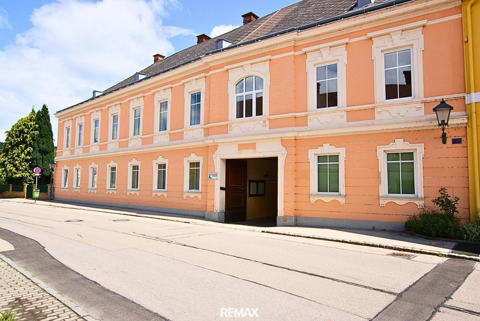 Historisches Gebäude mit einer markanten pfirsichfarbenen Fassade und vielen Fenstern.