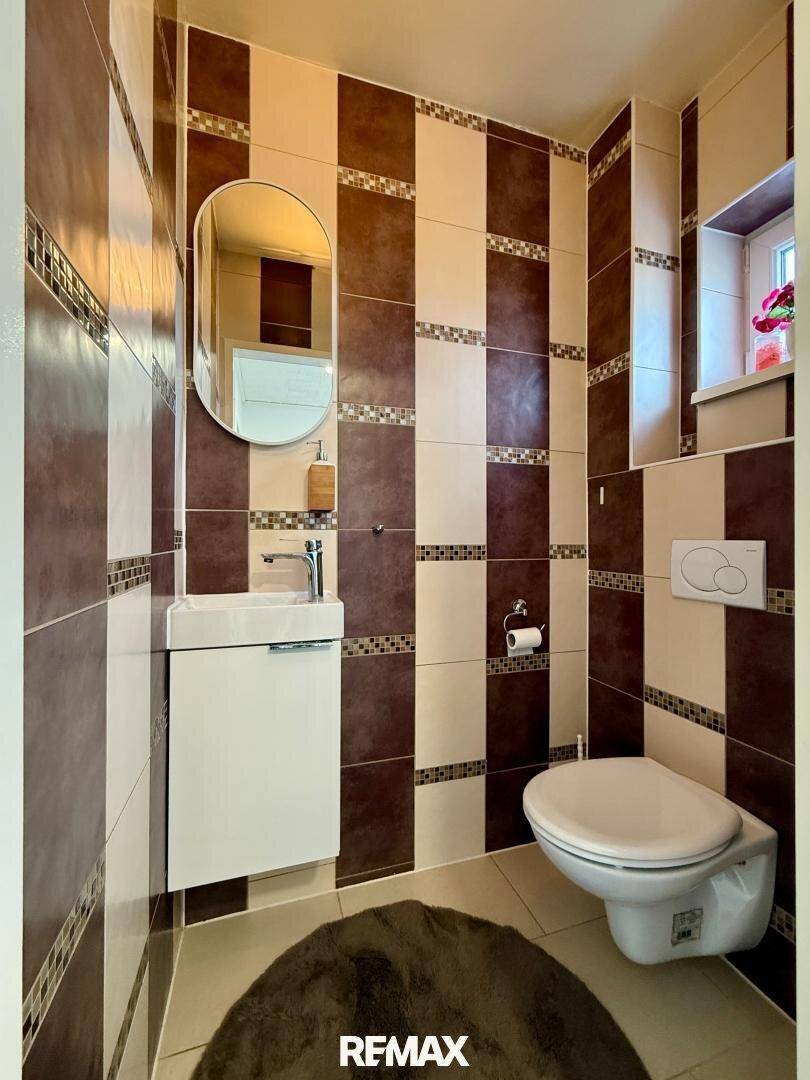 Kompaktes Gäste-WC mit modernen Fliesen in Braun- und Beigetönen und Wand-WC.