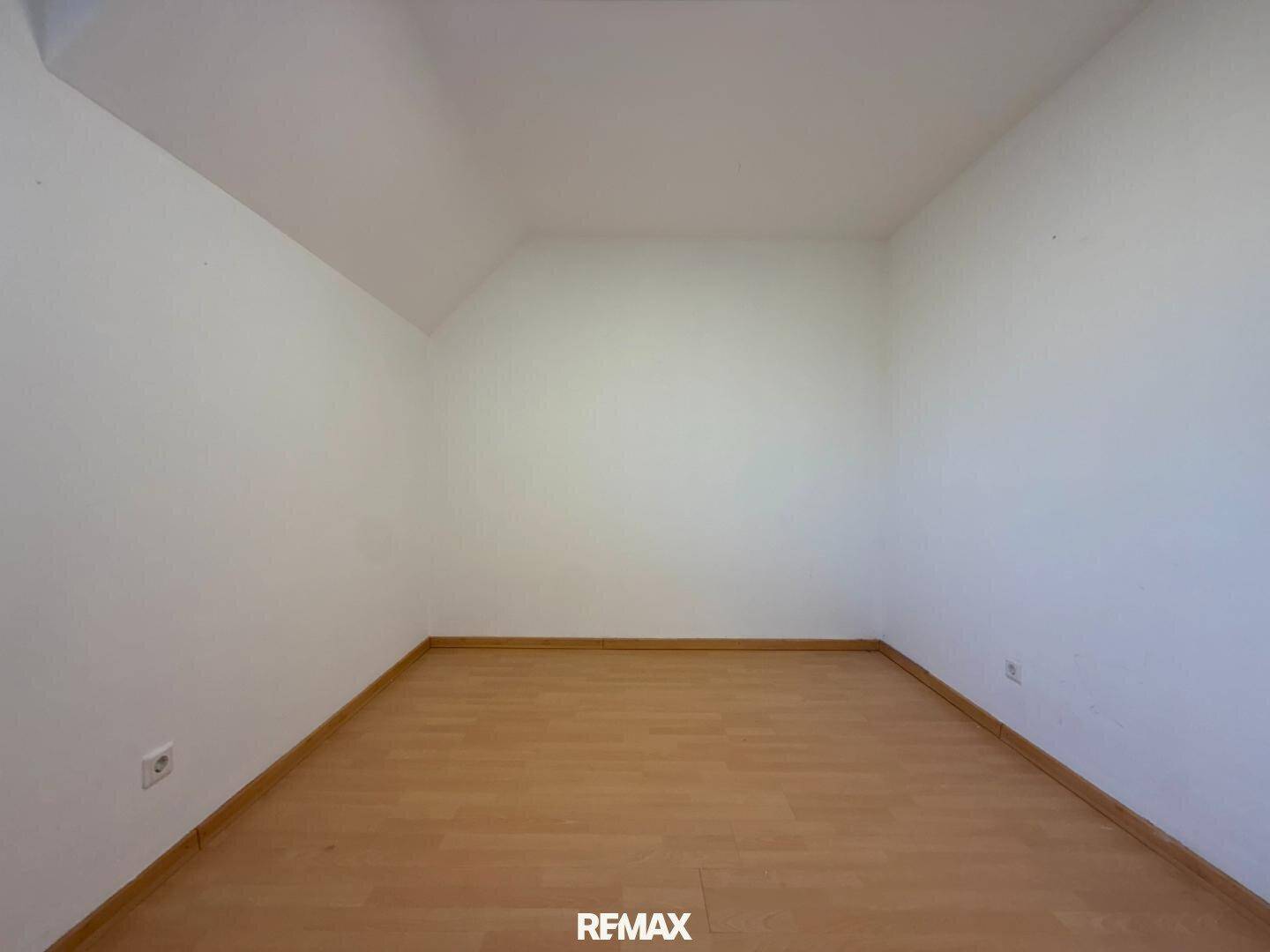 Helles, leeres Zimmer mit Dachschräge und Holzboden, ideal als Kinderzimmer.