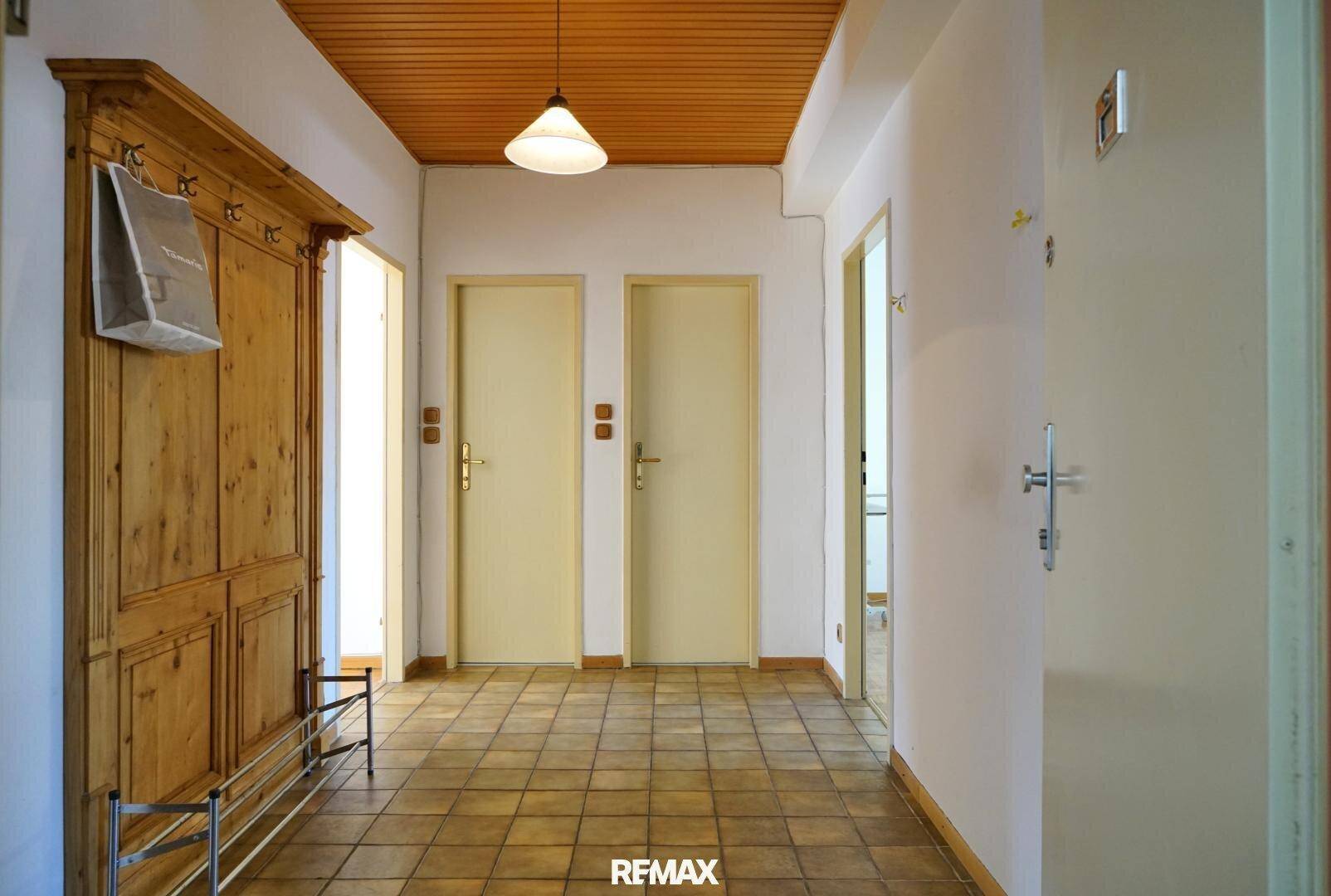 Geräumiger Flur mit traditionellem Holzschrank, Fliesenboden und Holzdecke.
