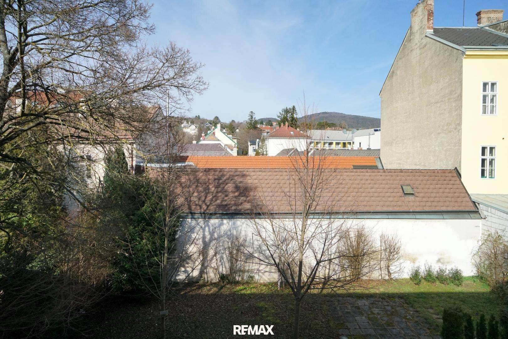 Blick aus dem Fenster auf die umliegende Nachbarschaft mit Dächern und Bäumen.