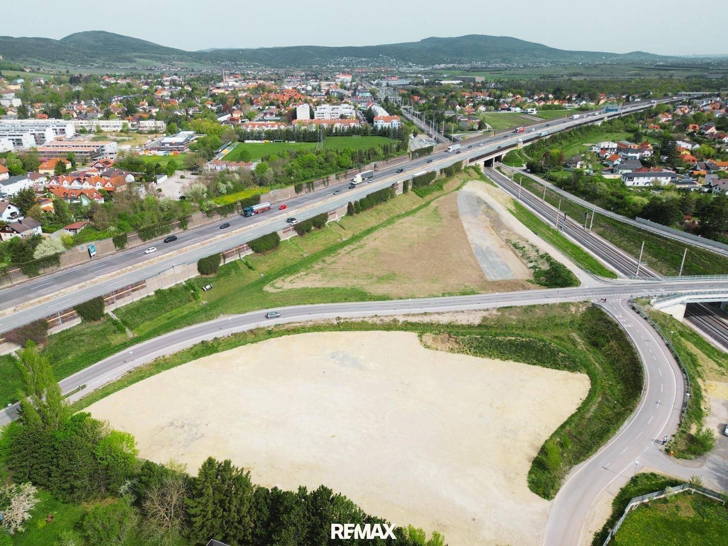 Umfassende Luftansicht eines unbebauten Grundstücks mit Verkehrsanbindung und städtischer Umgebung.
