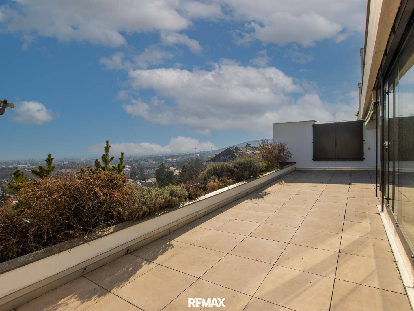 Geräumige Dachterrasse mit Fliesenboden und weitem Blick über die Stadt und die Umgebung.