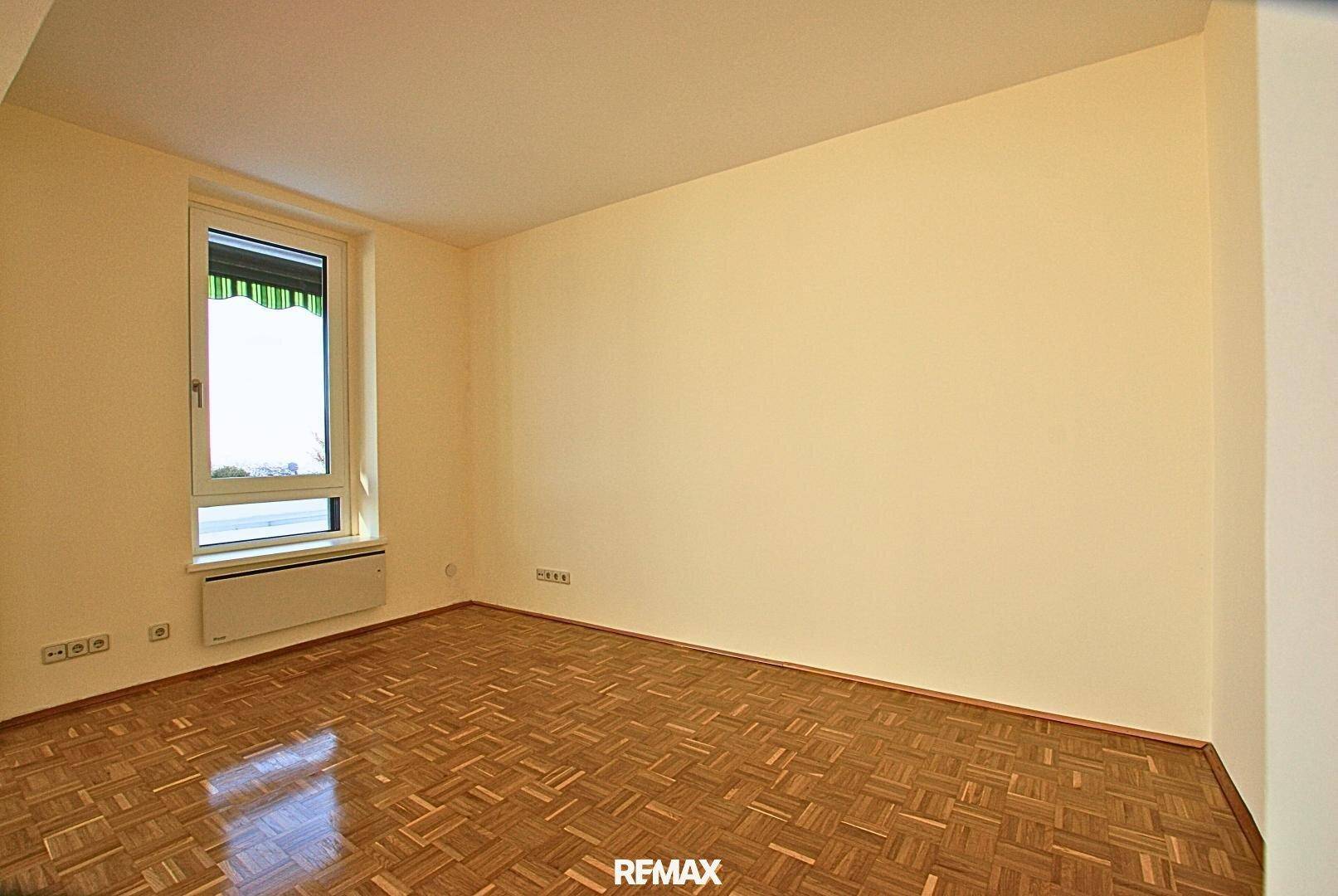 Leeres Zimmer mit Parkettboden und einem Fenster, bereit zur individuellen Gestaltung.