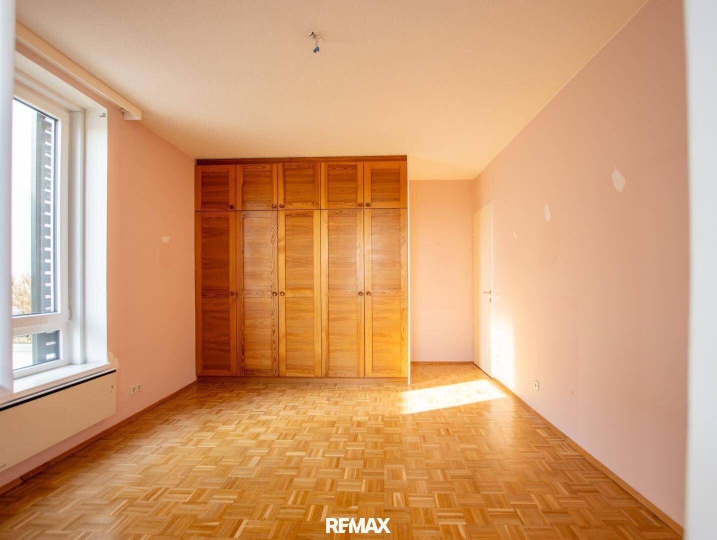 Helles Zimmer mit Einbauschränken aus Holz und Parkettboden, ideal für Schlafzimmernutzung.
