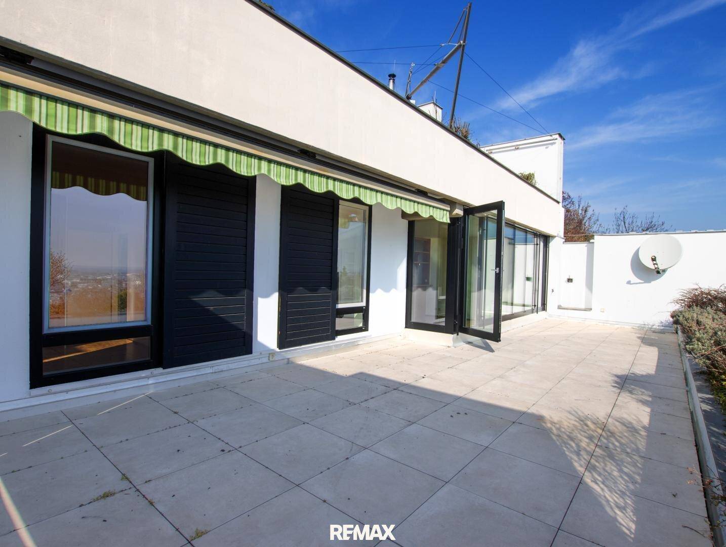 Weitläufige Terrasse mit großen Fenstern und Zugang zu den Innenräumen, ideal für Entspannung.