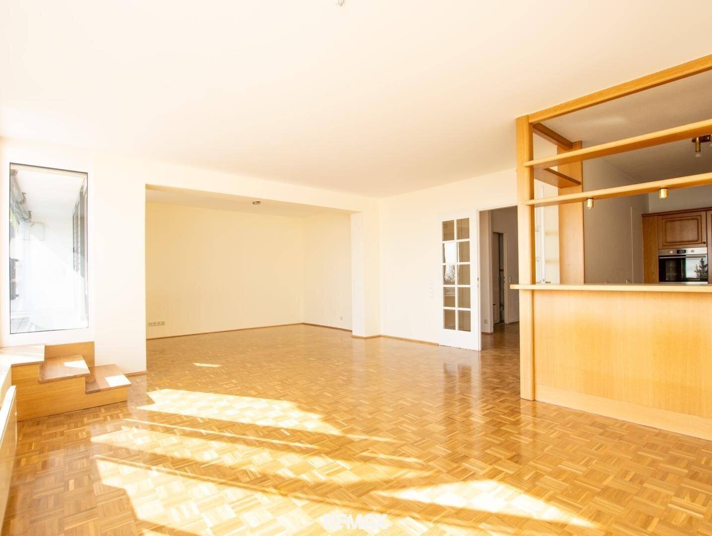 Großzügiges, lichtdurchflutetes Wohnzimmer mit Parkettboden und offener Gestaltung.