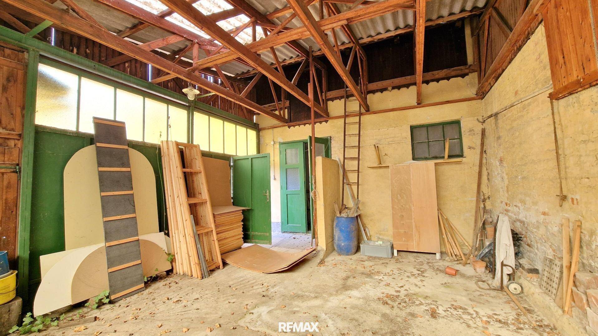 Großer rustikaler Raum mit hohen Holzdecken und gelagerten Baumaterialien, ideal als Werkstatt.
