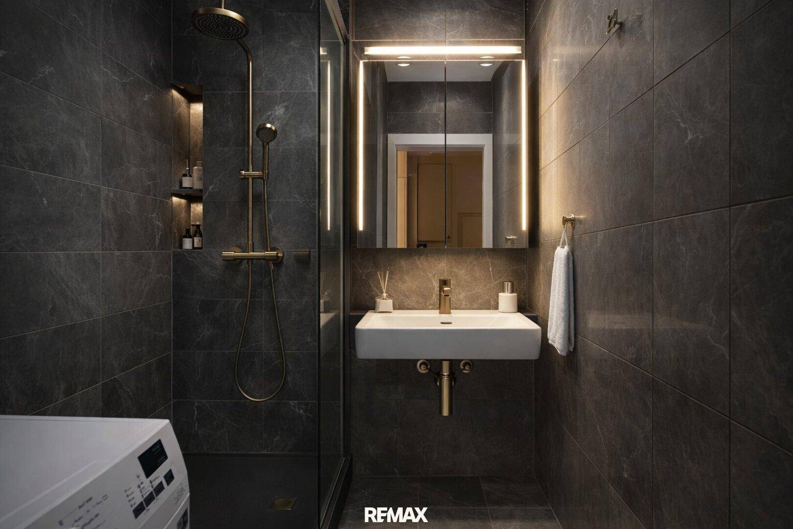Modernes Badezimmer mit dunklen Fliesen, goldfarbenen Armaturen und beleuchtetem Spiegelschrank.
