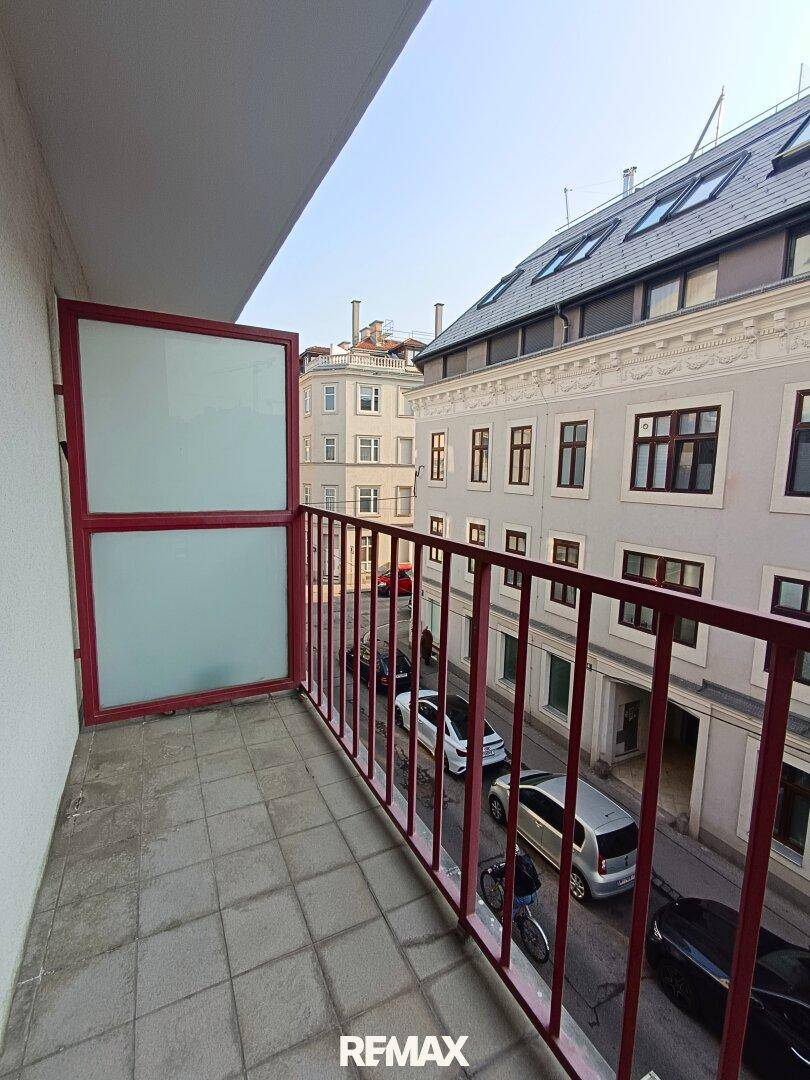 Balkon mit rotem Geländer und Blick auf die belebte Stadtstraße.