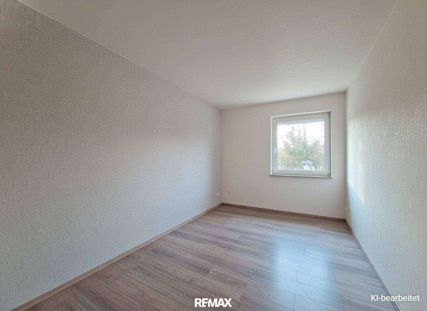Leeres Zimmer mit hellem Laminatboden und einem Fenster, bereit zur individuellen Gestaltung.