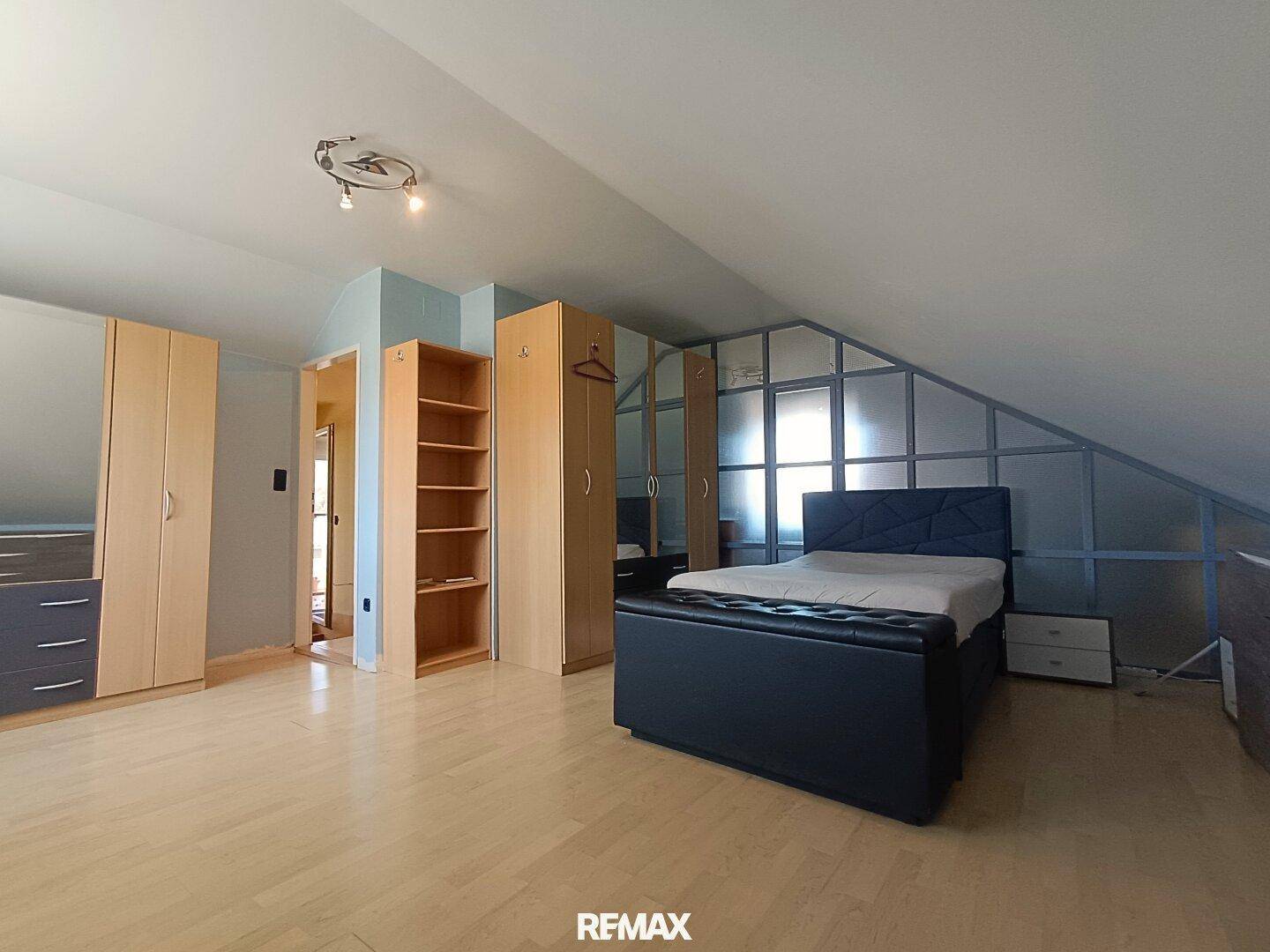 Gemütliches Schlafzimmer im Dachgeschoss mit Dachschräge, Laminatboden und praktischen Kleiderschränken.
