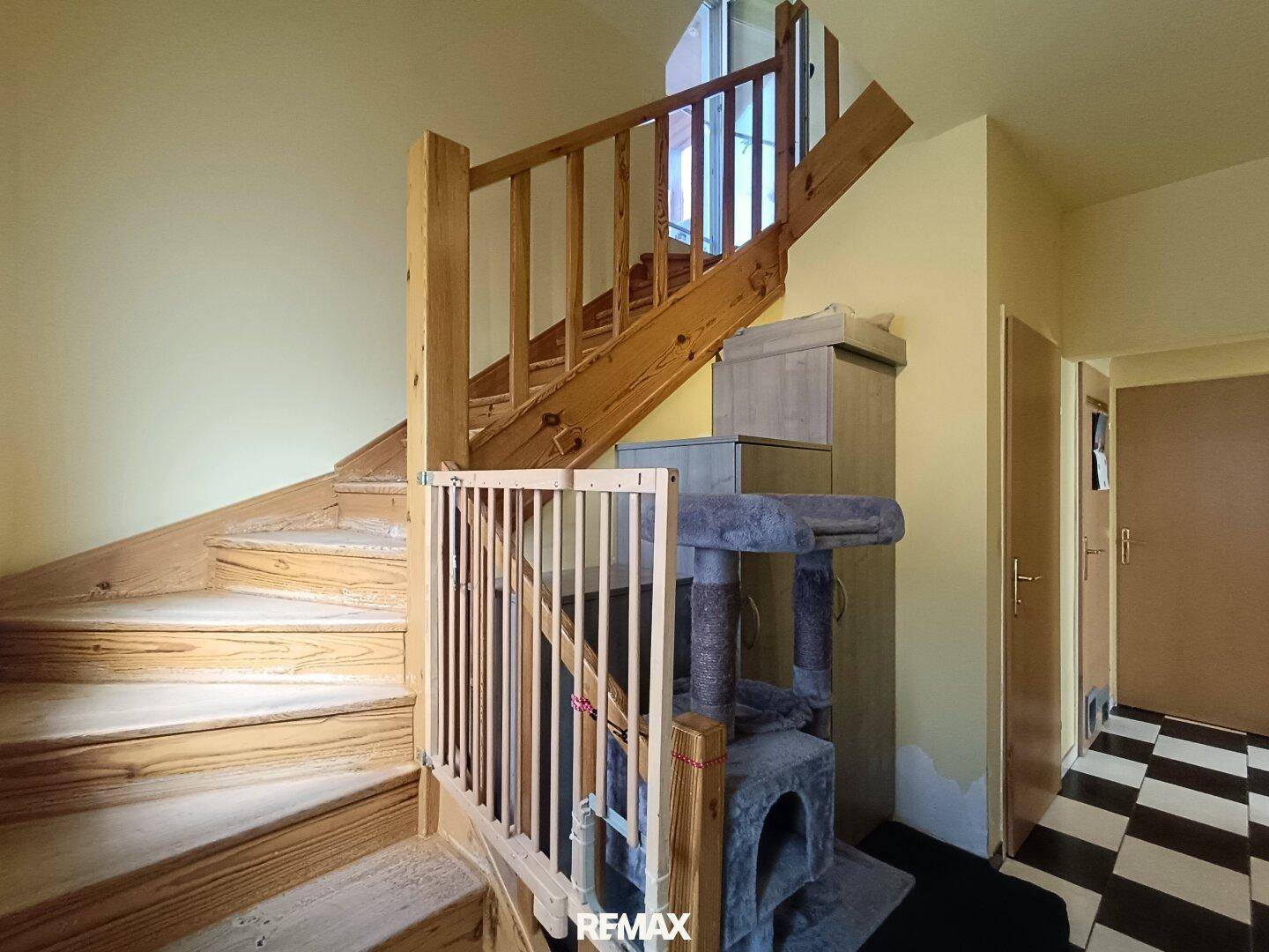 Helle Holztreppe mit Geländer und Kinderschutzgitter, führt in die obere Etage des Hauses.
