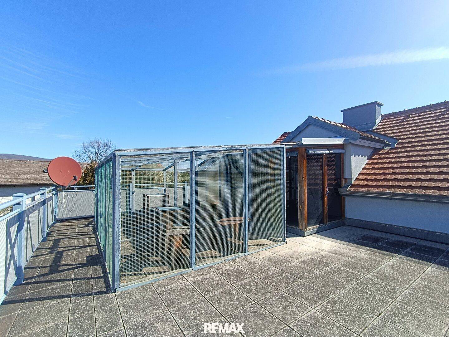 Geräumige Dachterrasse mit Fliesenboden und einer überdachten Gitterkonstruktion, ideal für Outdoor-Aktivitäten.