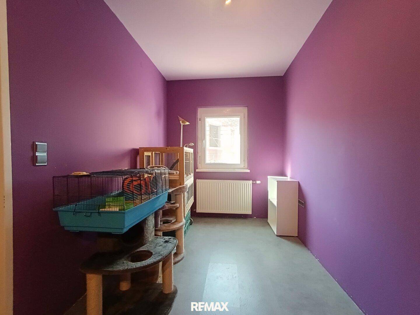 Zimmer mit auffälligen violetten Wänden, Fenster und Platz für individuelle Gestaltung, hell und freundlich.