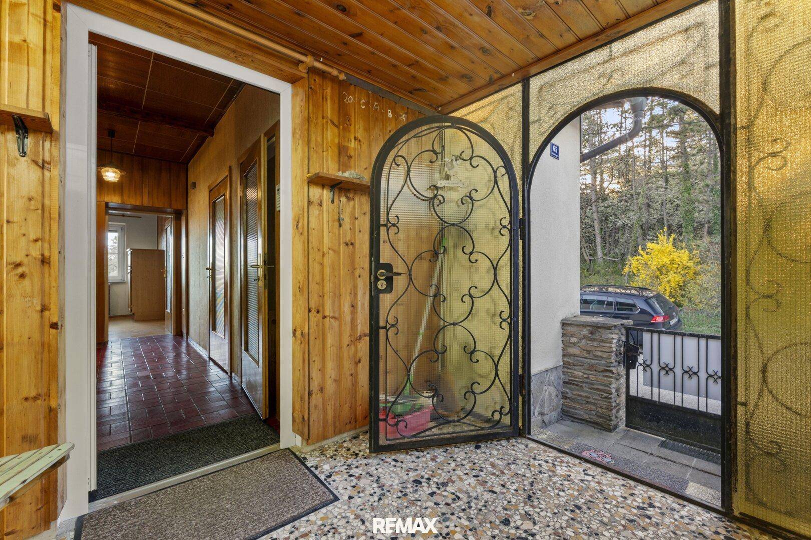 Eingangsbereich mit Terrazzoboden und Holzwänden, der zu weiteren Räumen führt.