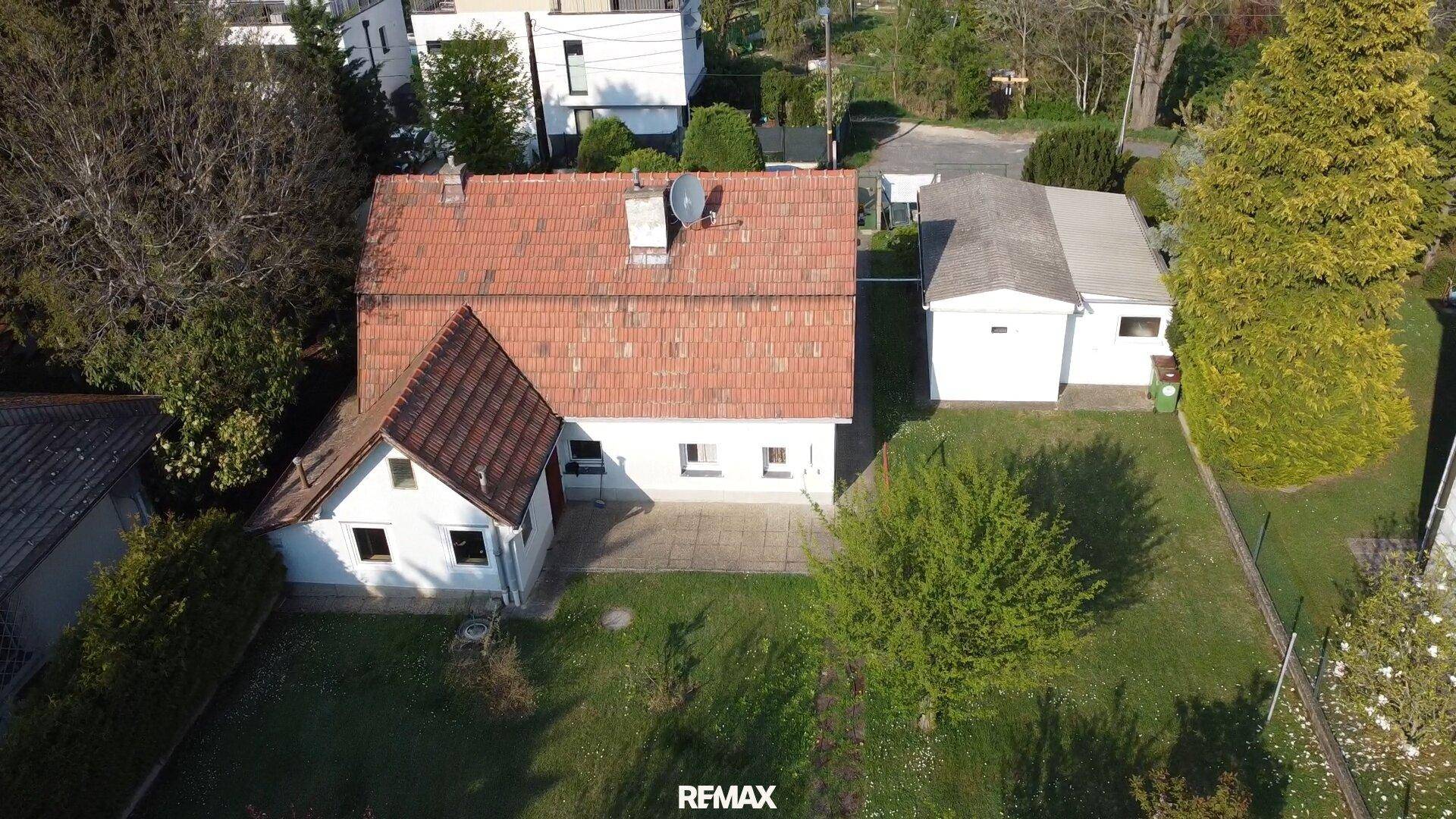 Luftaufnahme eines Einfamilienhauses mit rotem Ziegeldach und großem Gartenbereich.