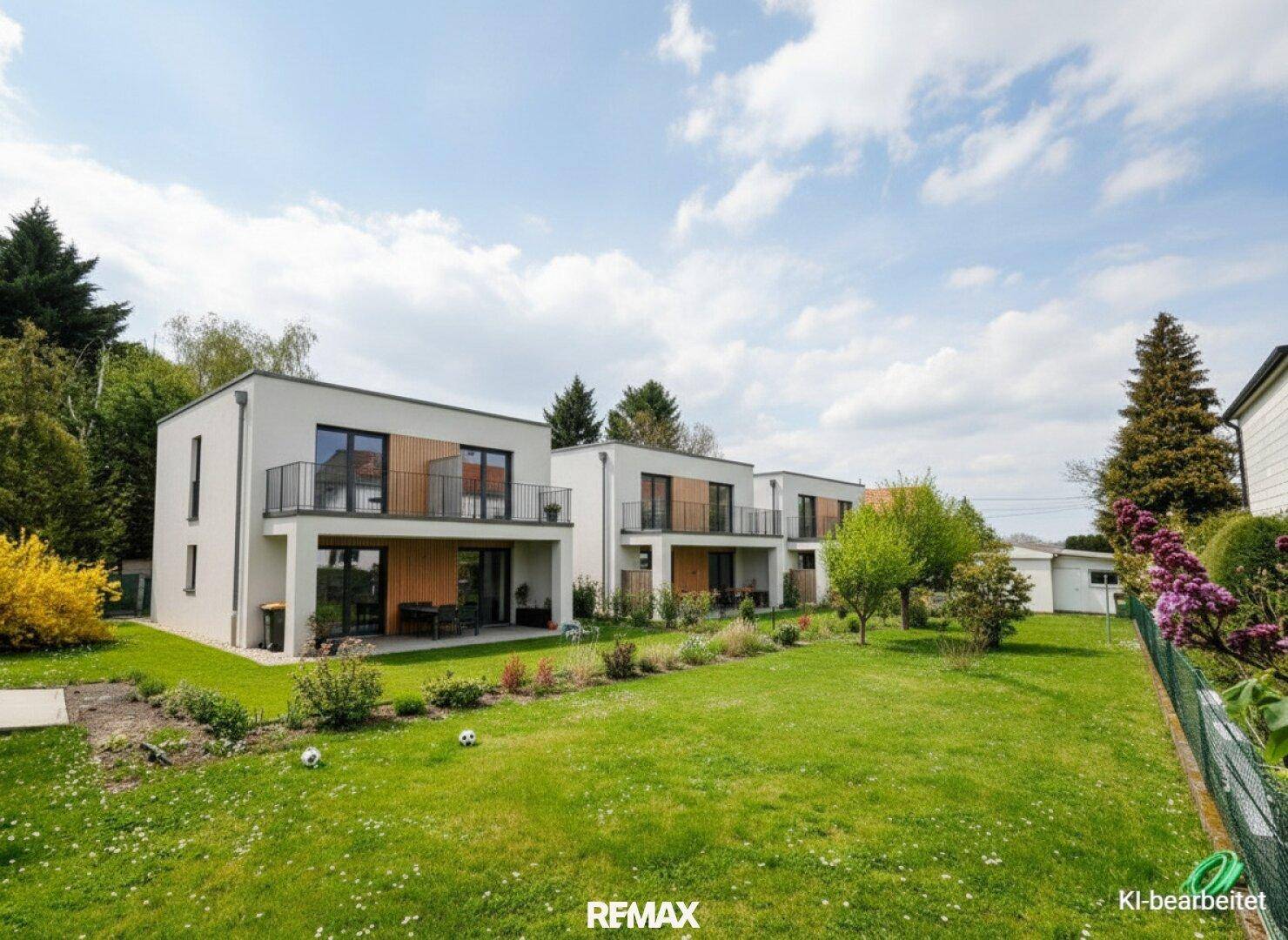 Reihe moderner Häuser mit Balkonen und einem gemeinsamen, gepflegten Gartenbereich.