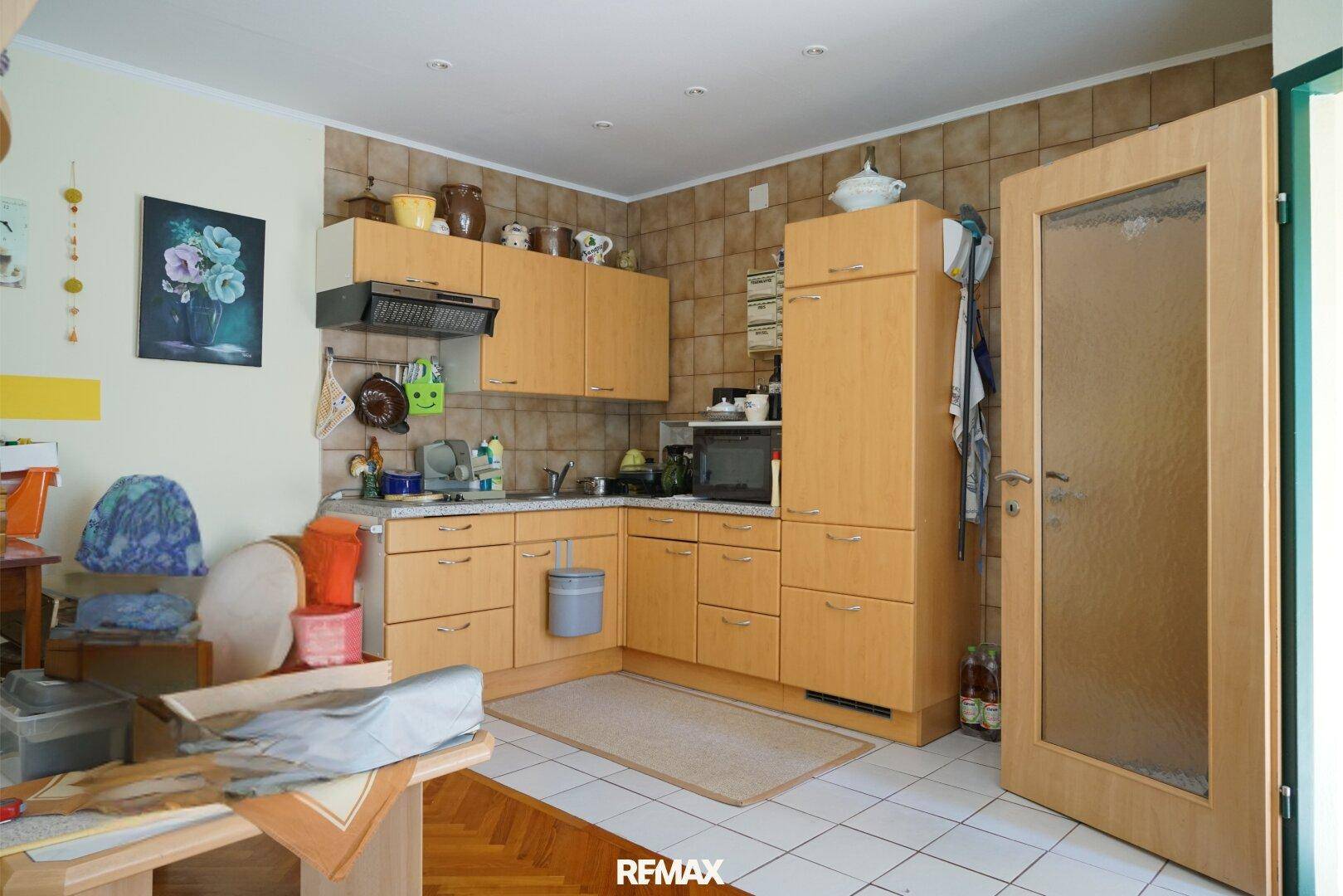 Geräumige Küche mit Holzschränken, Fliesenboden und Zugang zum Garten.