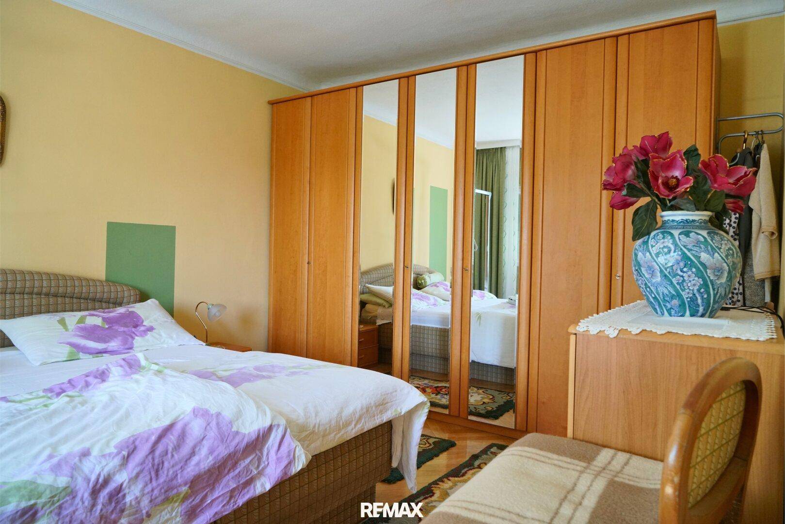 Gemütliches Schlafzimmer mit Doppelbett, Holzschrank und Spiegeltüren.