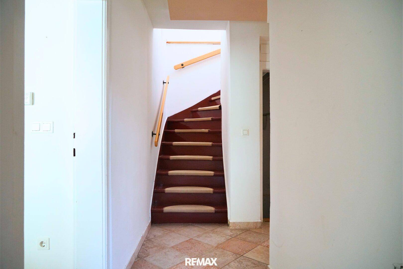 Heller Flur mit Treppe ins Obergeschoss und Fliesenboden im Eingangsbereich.
