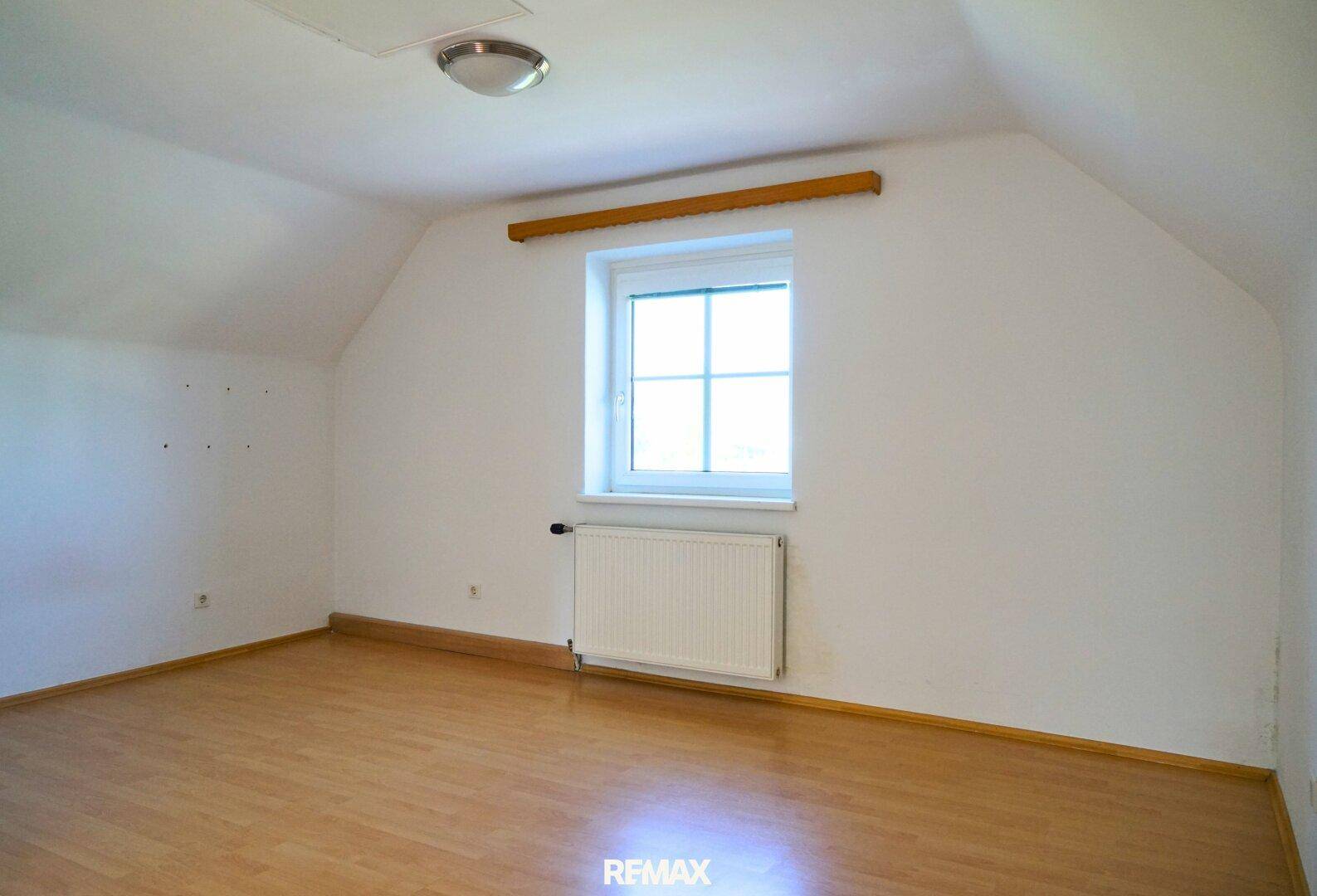 Helles Schlafzimmer im Dachgeschoss mit Schrägen, Laminatboden und Fenster.