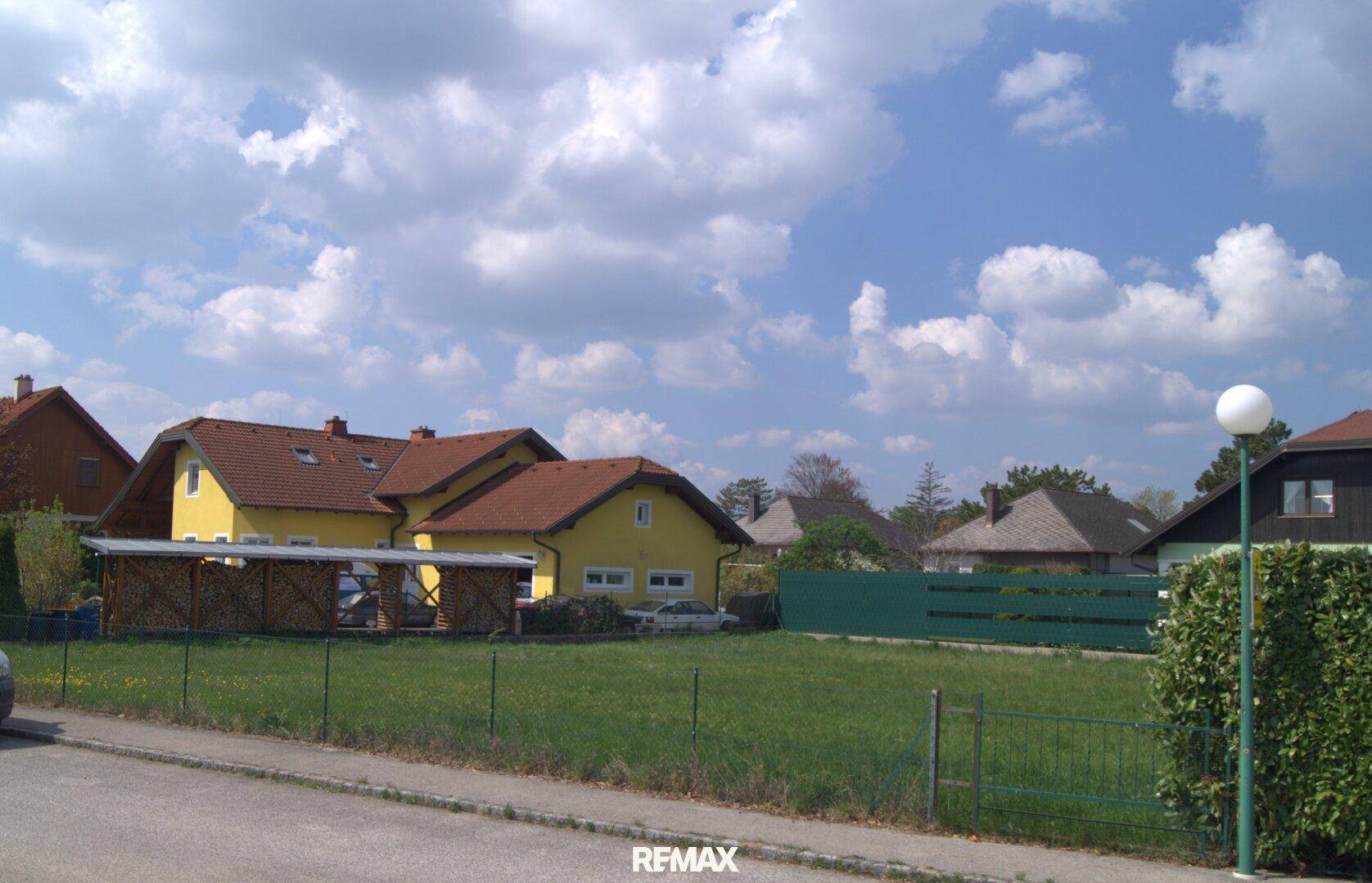 Blick auf eine ländliche Wohngegend mit älteren Häusern und einer großen Grünfläche im Vordergrund.
