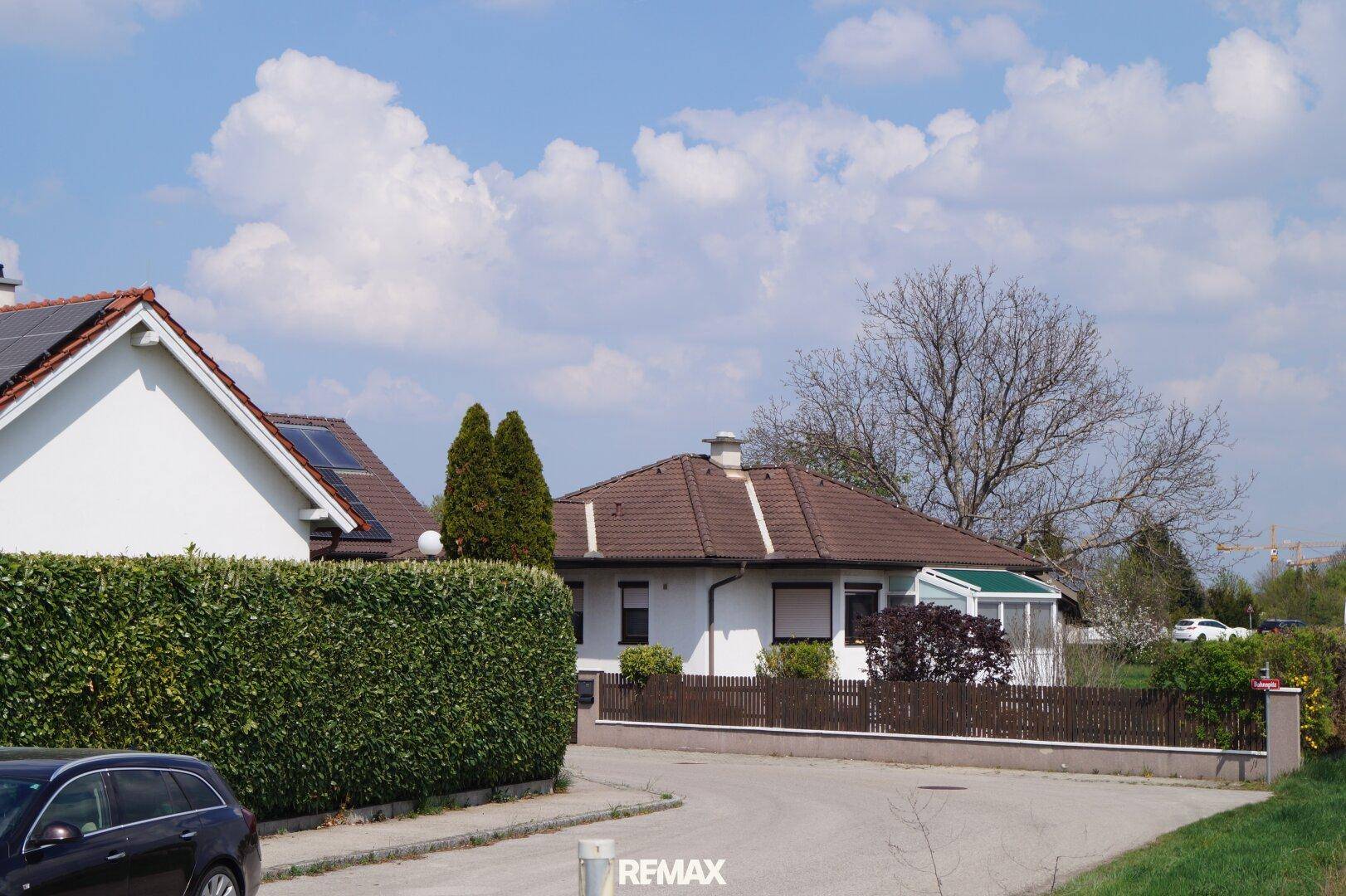 Wohnhaus mit braunem Ziegeldach und gepflegtem Gartenbereich an einer ruhigen Wohnstraße.