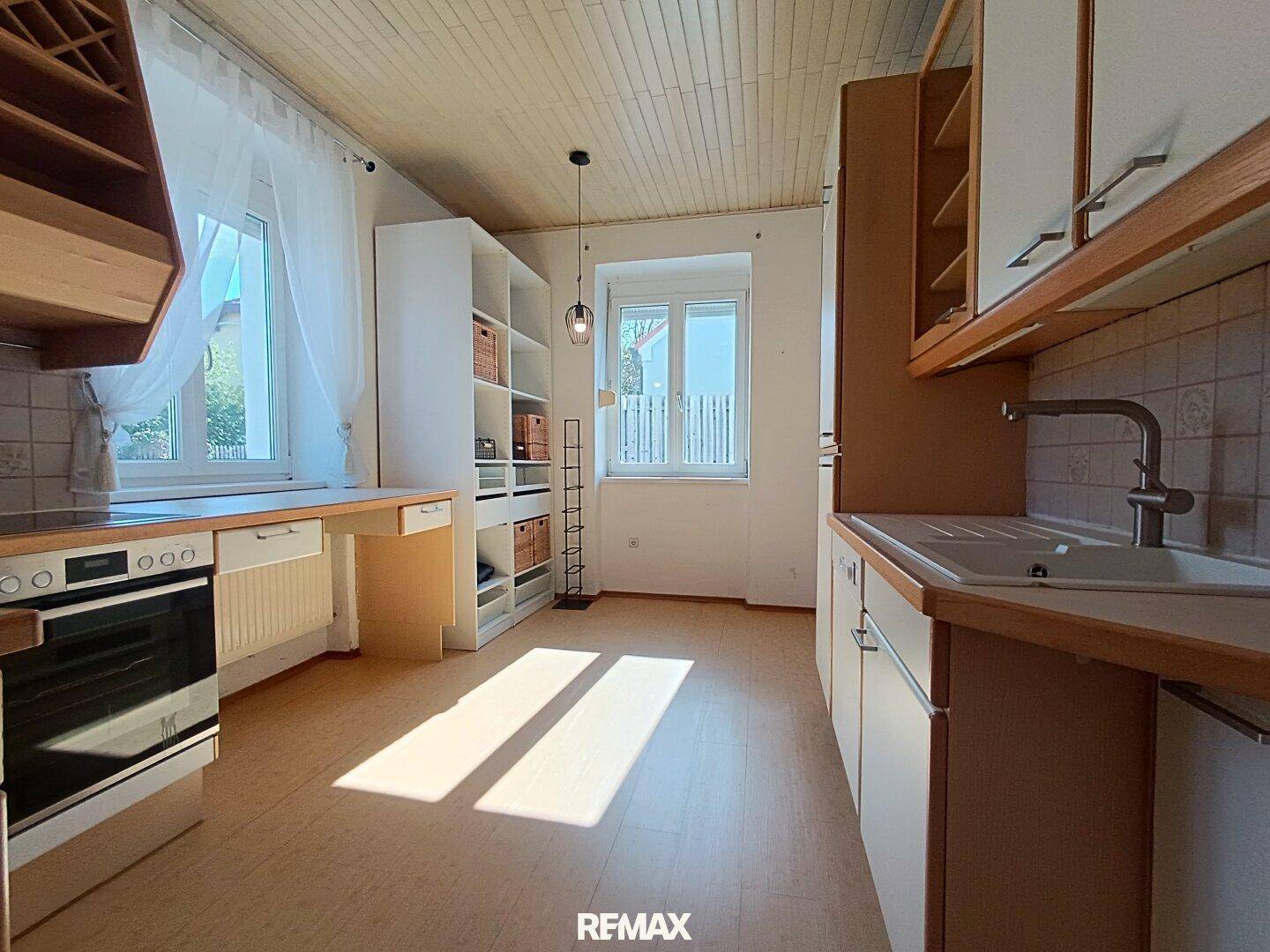 Helle Küche mit Holzdecke, Einbauschränken und Laminatboden.