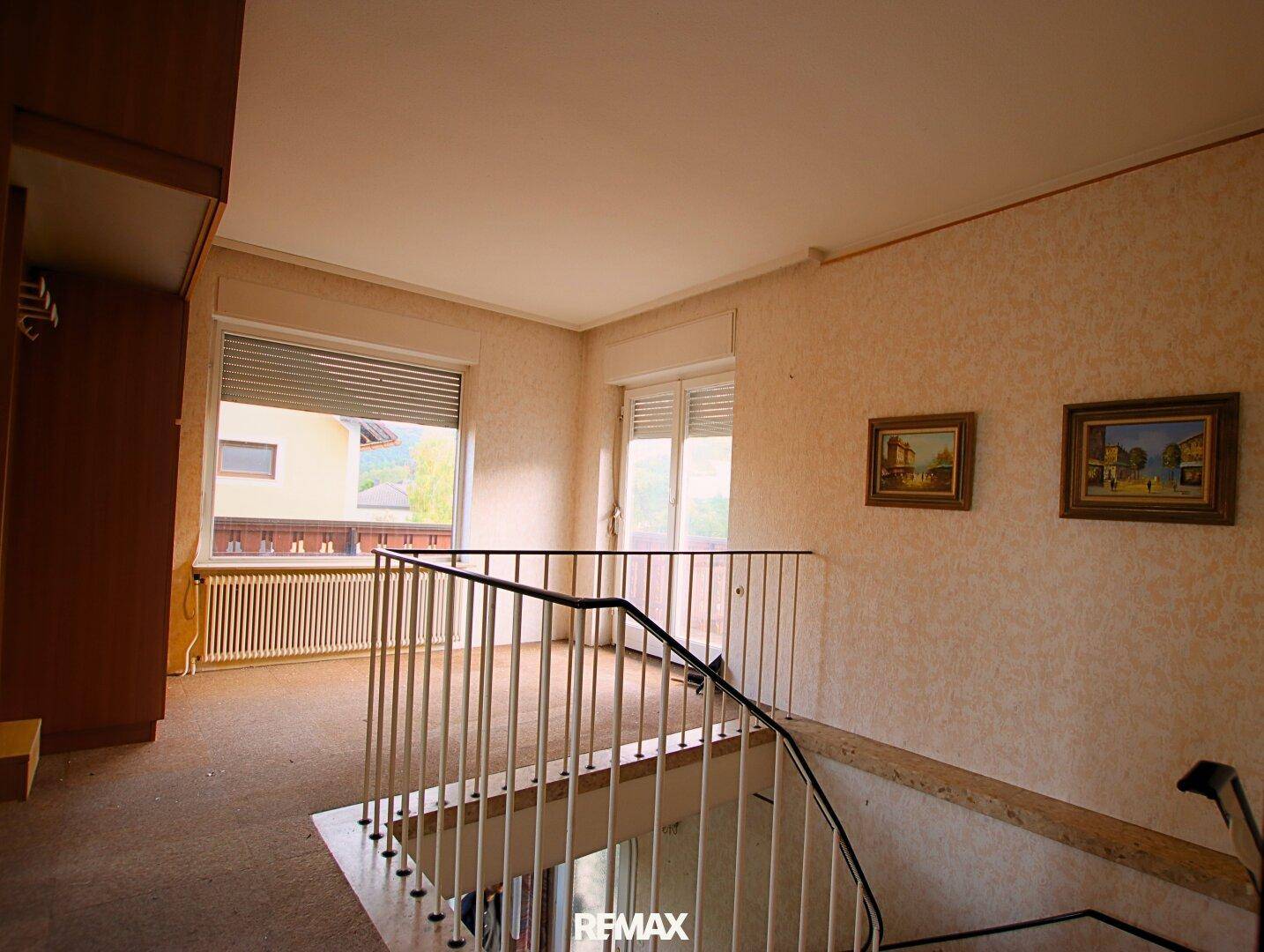 Heller Flurbereich im Obergeschoss mit Treppengeländer und Fenstern, die den Raum mit Tageslicht füllen.