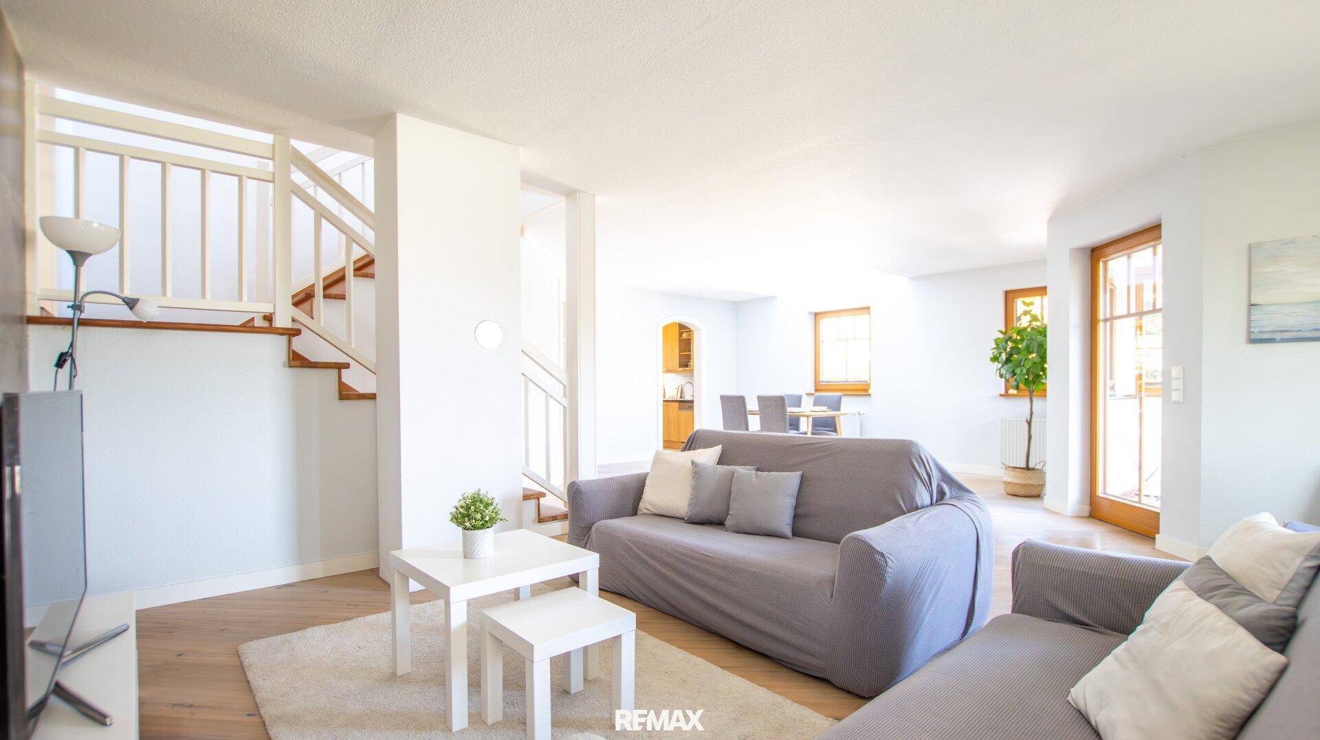 Helles Wohnzimmer mit bequemen Sofas, Couchtisch und offenem Zugang zum Treppenhaus.