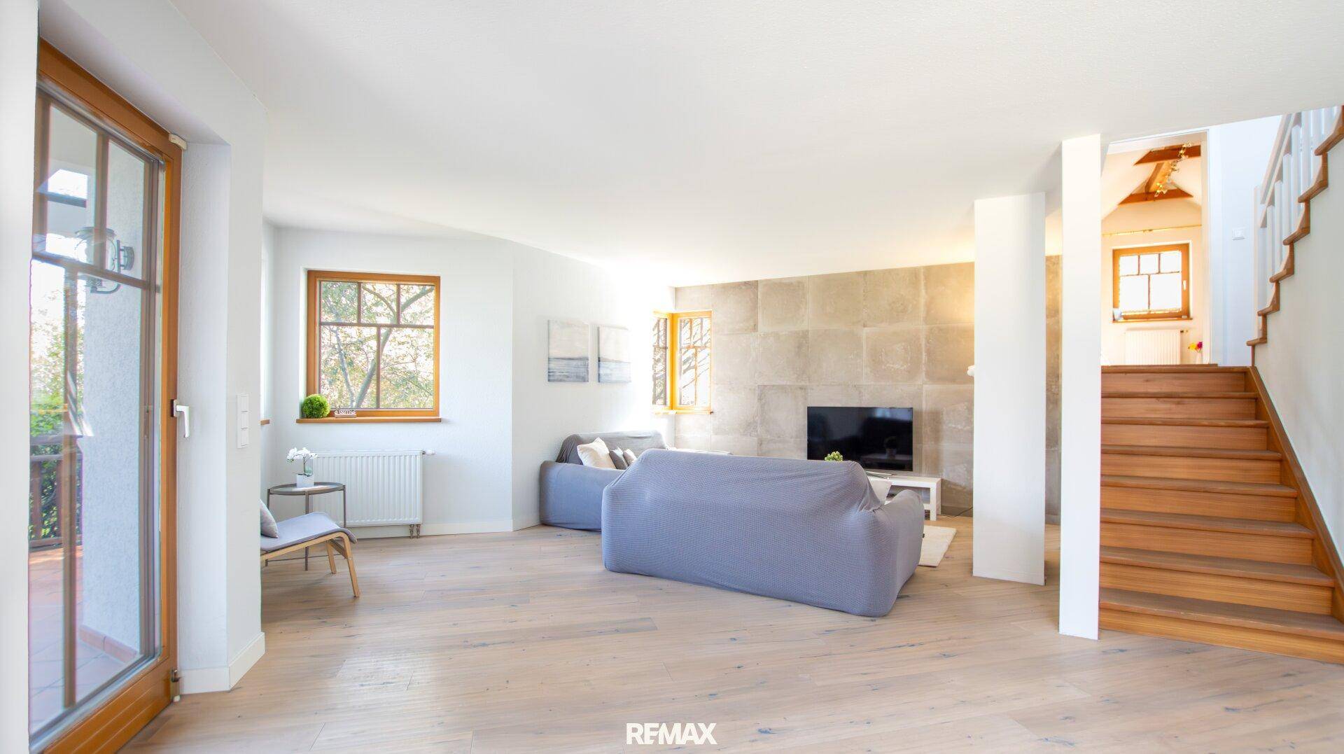 Gemütliches Wohnzimmer mit hellen Sofas, Holzboden und Zugang zum Außenbereich.