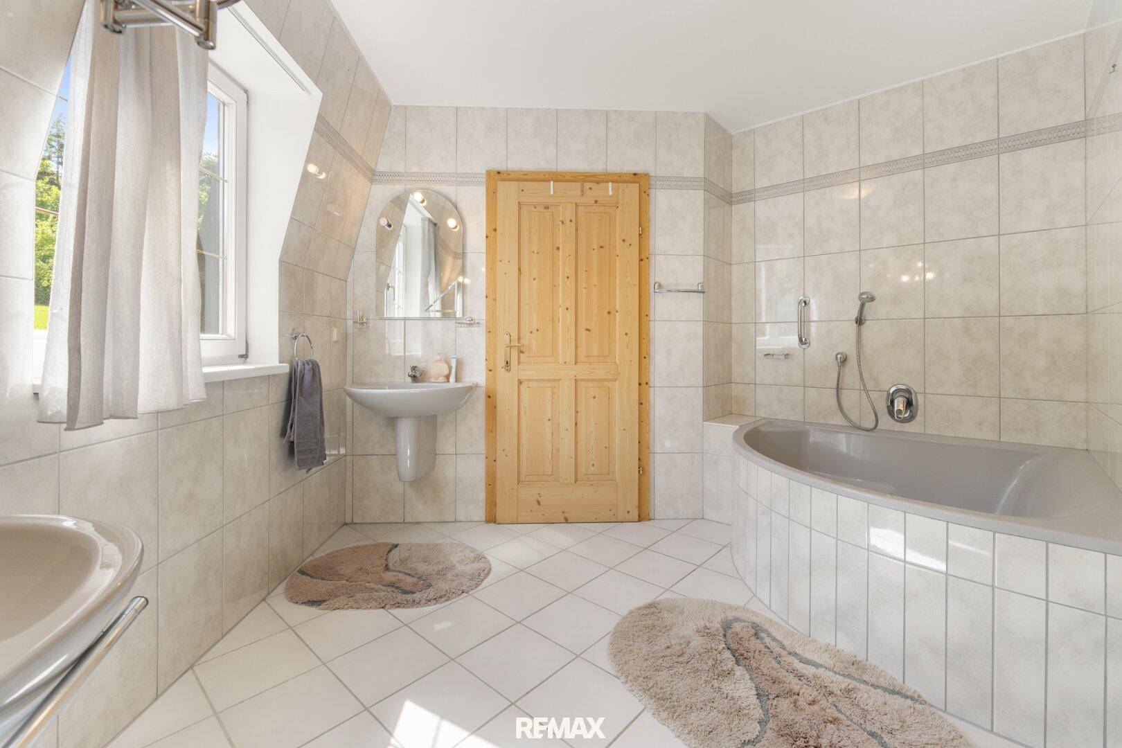 Geräumiges Badezimmer mit Eckbadewanne, Einzelwaschbecken und Fenster.