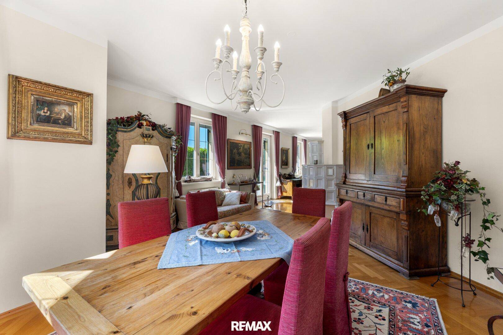Elegantes Esszimmer mit großem Holztisch, antiken Möbeln und Blick in den angrenzenden Wohnbereich.