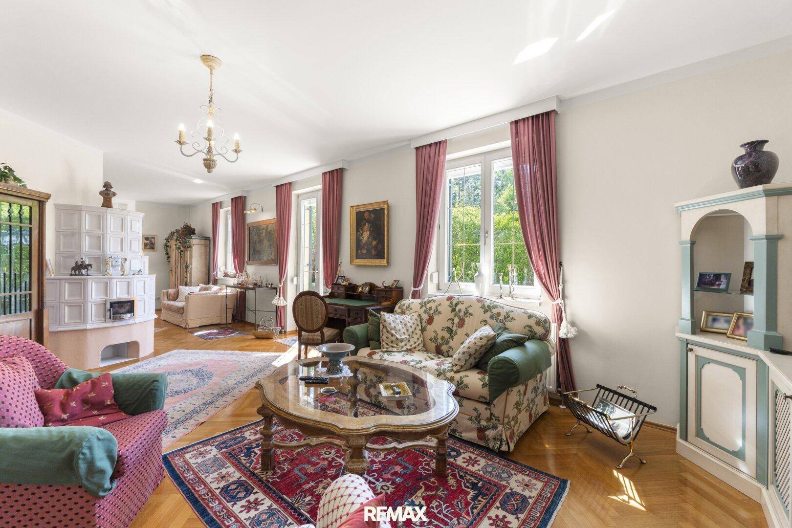 Helles Wohnzimmer mit Parkettboden, Kachelofen und traditionellen Möbeln.