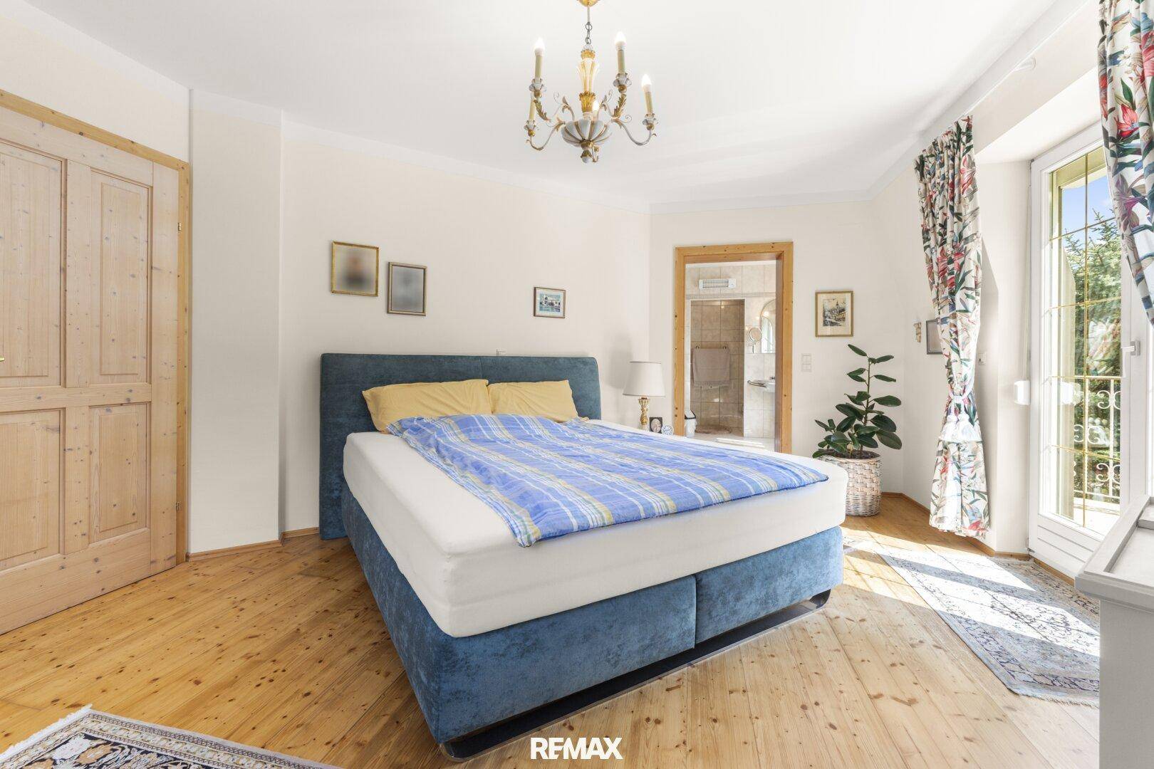 Schlafzimmer mit Holzboden, Doppelbett und direktem Zugang zum Balkon.