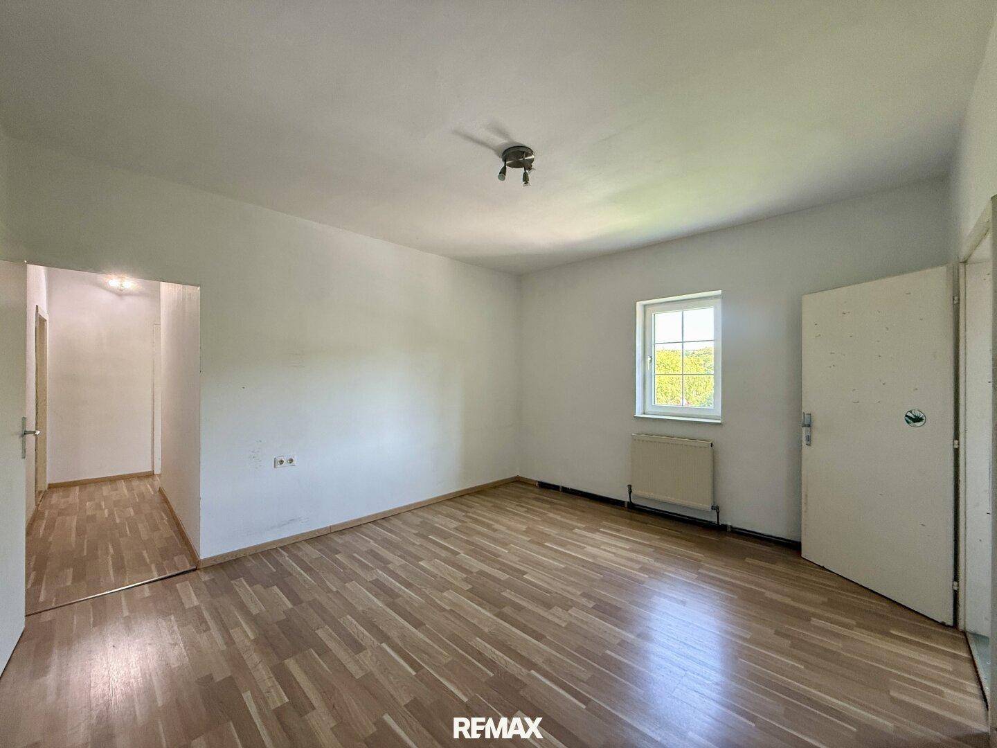 Geräumiges Zimmer mit Holzboden und Fenster, ideal als Schlaf- oder Arbeitszimmer.