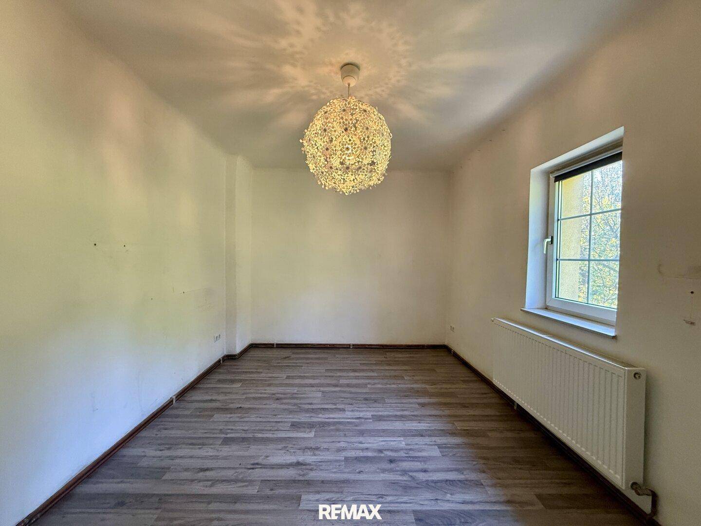 Leeres Zimmer mit modernem Bodenbelag und Fenster, vielseitig nutzbar.