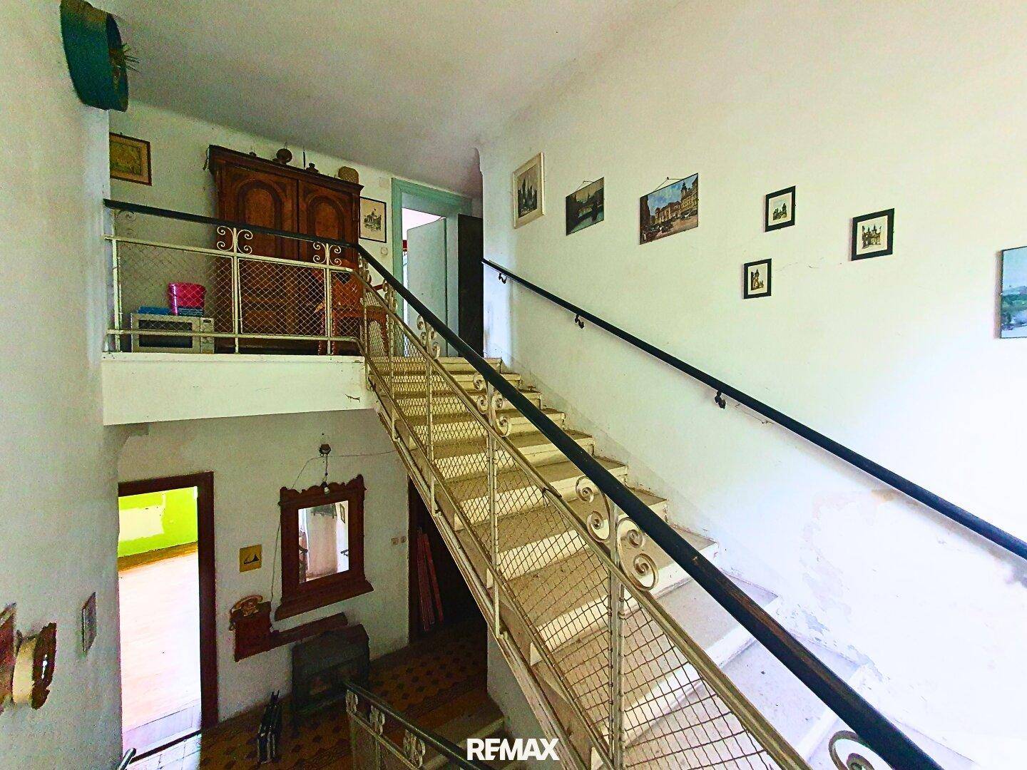 Heller Flur mit einer mehrstöckigen Treppe und Metallgeländer in einem Altbau.