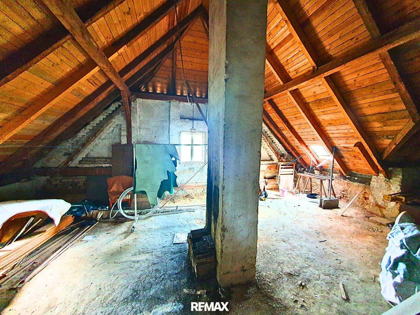 Geräumiger Dachboden mit sichtbaren Holzbalken und Dachschrägen, bereit für einen Ausbau.