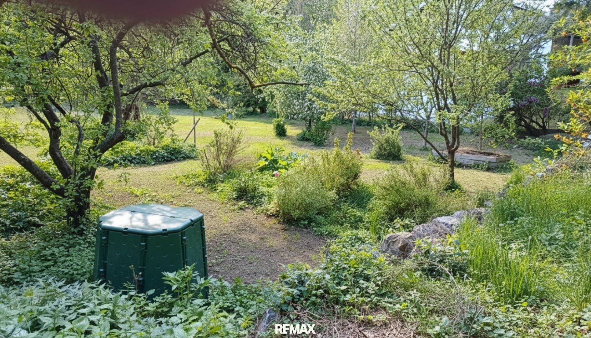 Naturbelassener Gartenbereich mit Komposter, Bäumen und vielfältiger Bepflanzung.