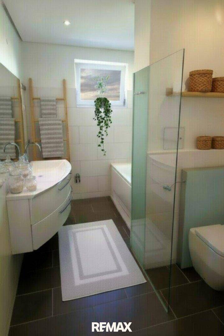 Modernes Badezimmer mit Badewanne, Dusche, Fenster und eleganten Fliesen.