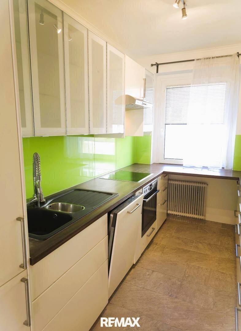 Funktionale Küche mit Fenster, Heizkörper und grüner Rückwand, bereit zur Nutzung.