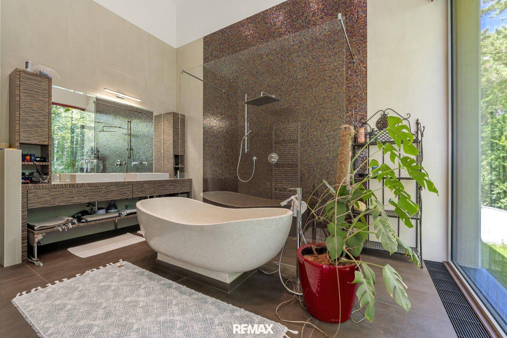 Luxuriöses Badezimmer mit freistehender Badewanne, großer Dusche und Mosaikfliesen.