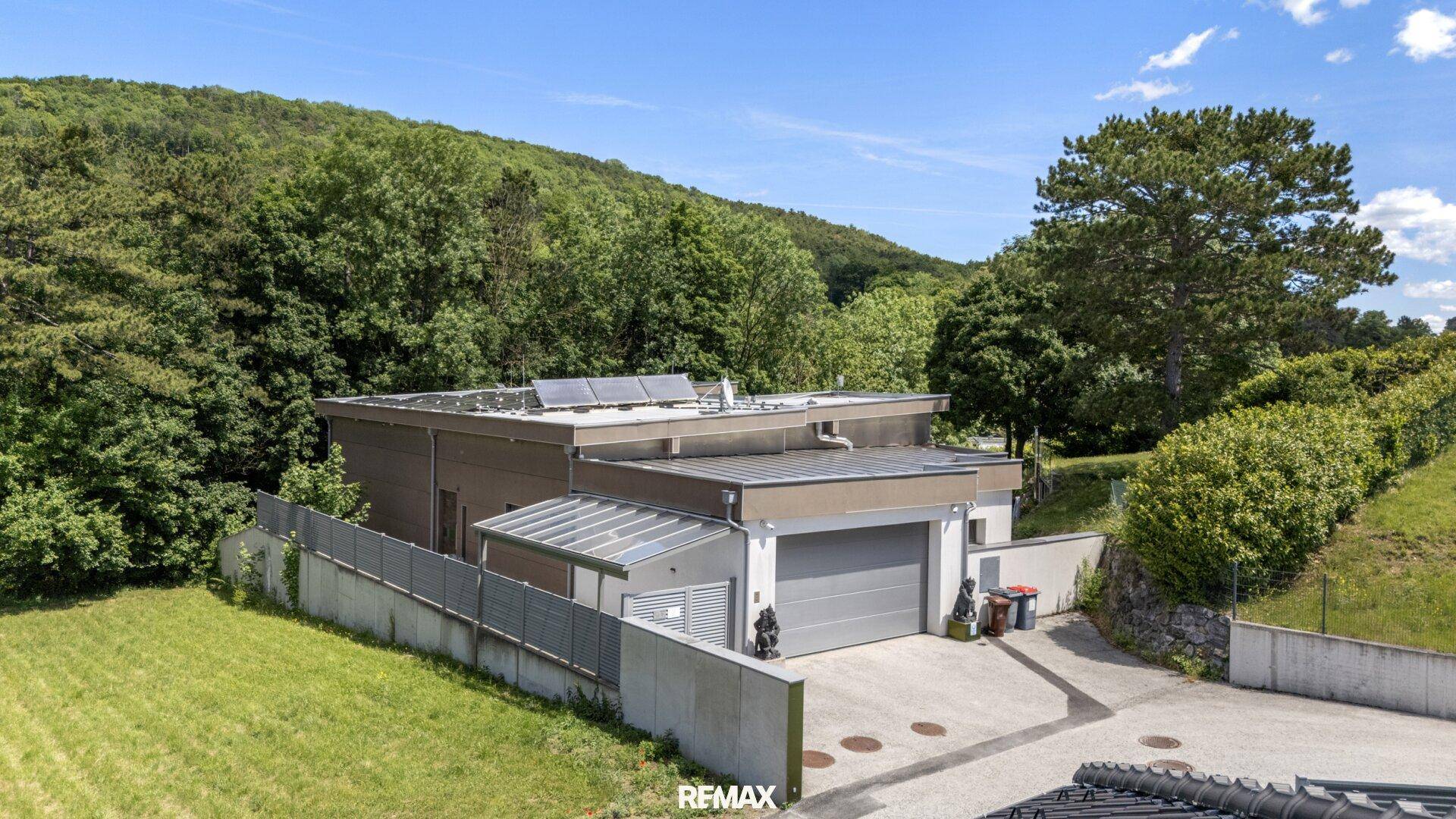 Modernes Einfamilienhaus mit Doppelgarage und Photovoltaikanlage in grüner Umgebung.