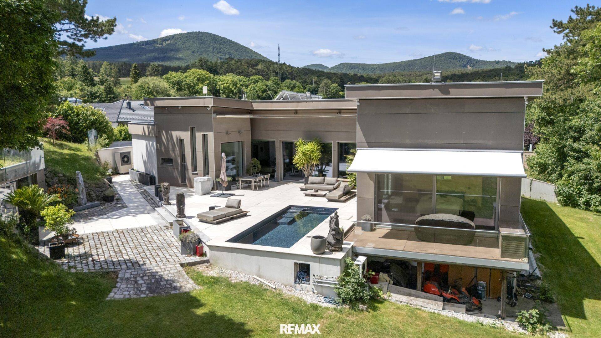 Moderne Villa mit Pool, großer Terrasse und weitem Blick auf die umliegende grüne Landschaft und Berge.