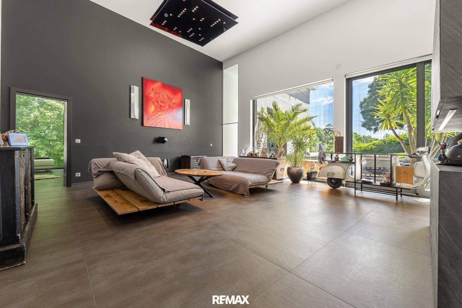 Geräumiges Wohnzimmer mit hohen Decken, großen Fenstern und modernem Design.