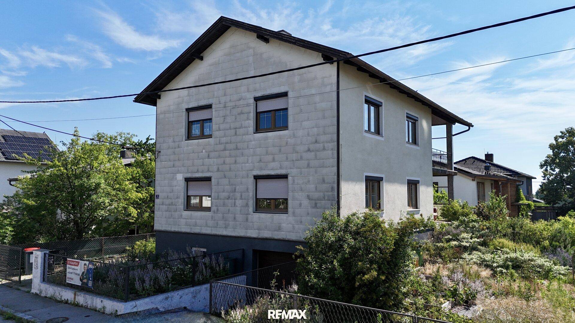 Ansicht des Einfamilienhauses von der Seite mit Balkon und Gartenbereich.